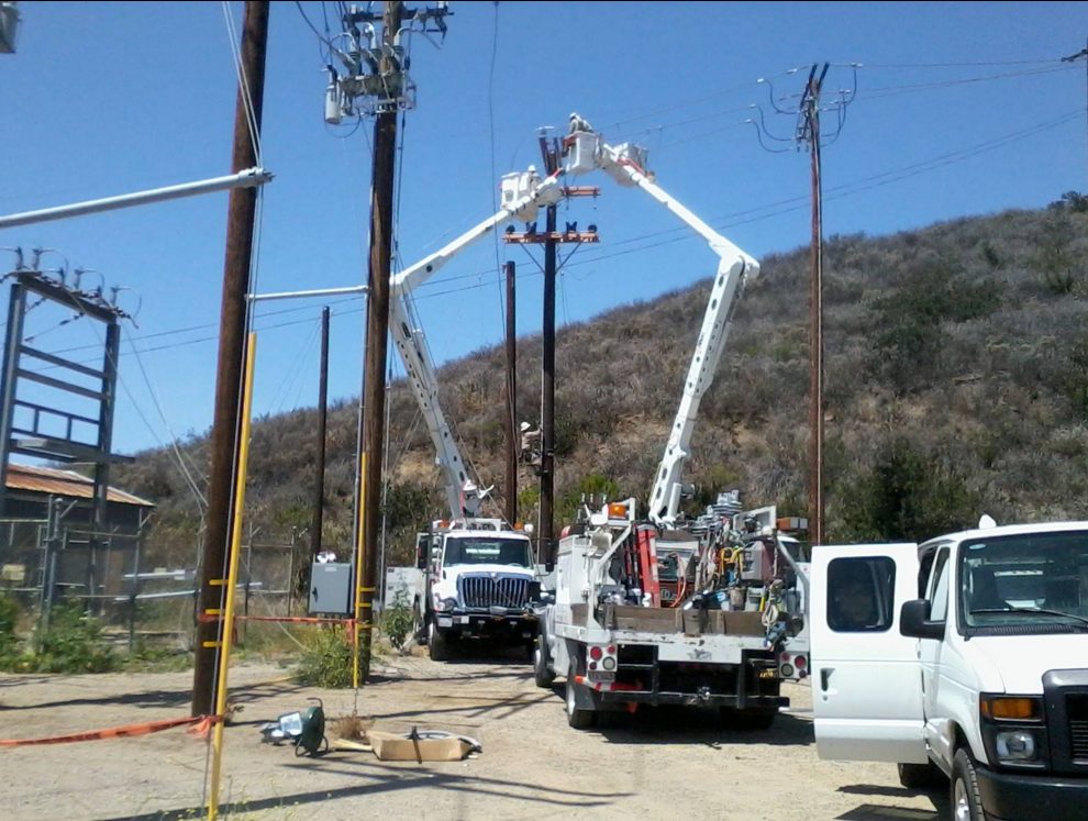 Oilfield Electric crews working from bucket trucks on utility poles