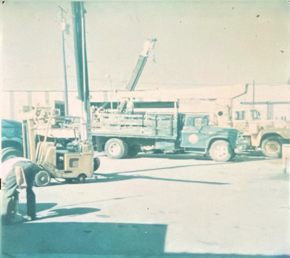 OEC blue field trucks and a crew working in the yard, 1960s