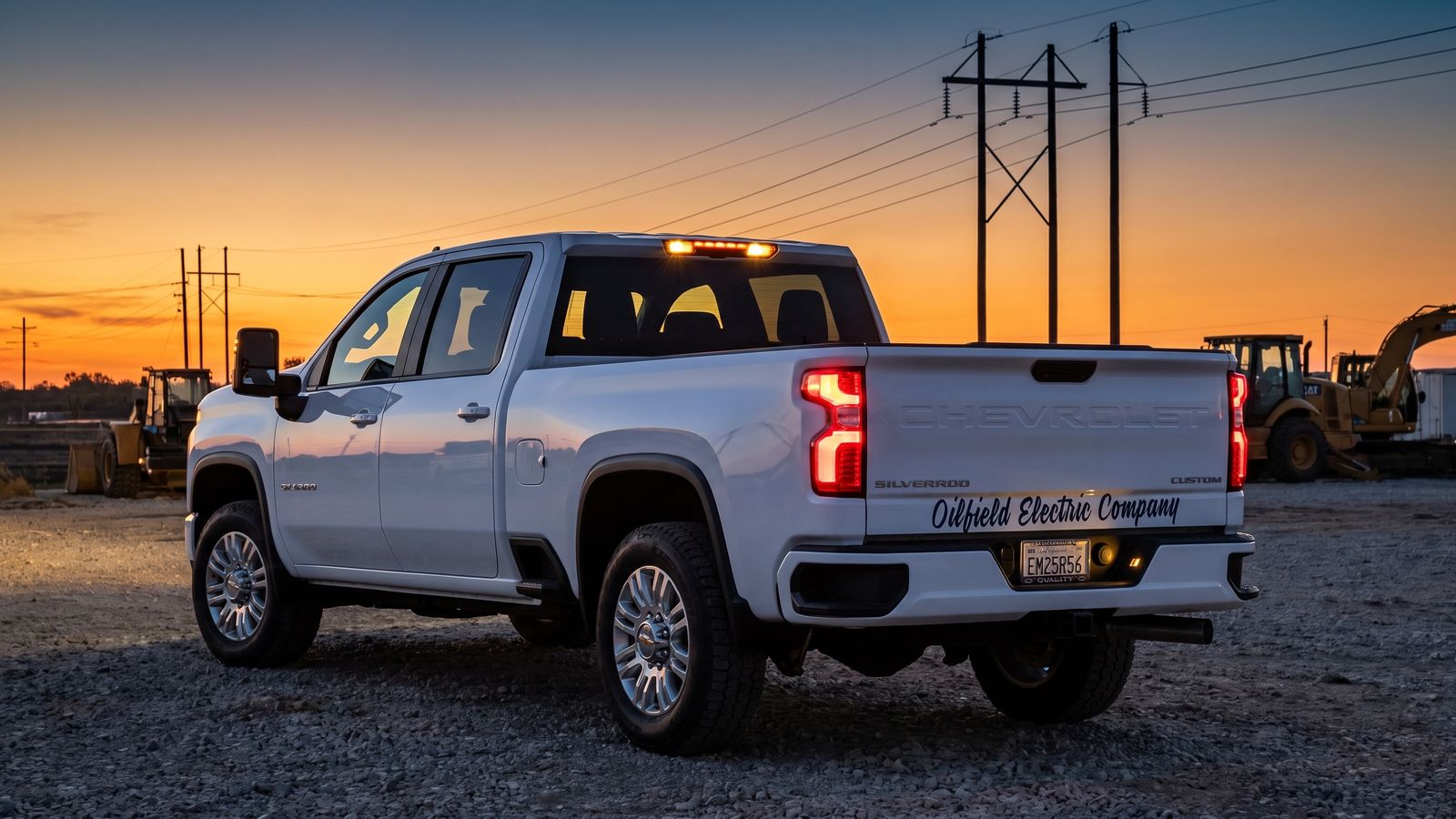 White OEC Electrical Chevrolet Silverado service truck at dusk with roof marker lights on at a job site